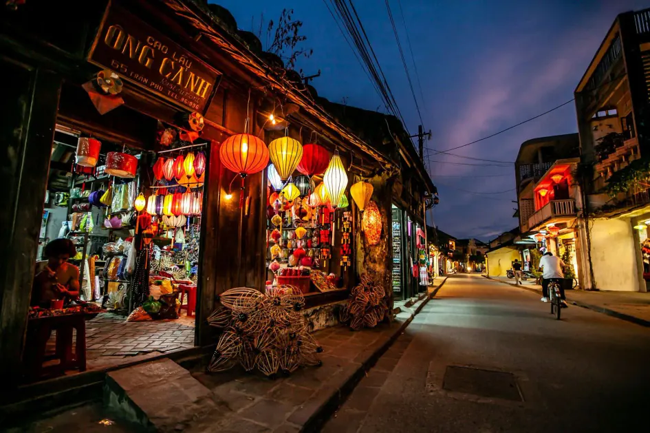 Una tienda de farolillos encendidos en una calle del casco viejo de Hoi An, al anochecer